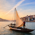Barco rabelo no rio Douro a ajustar as velas, metáfora da comunicação estratégica da 4 Ventos